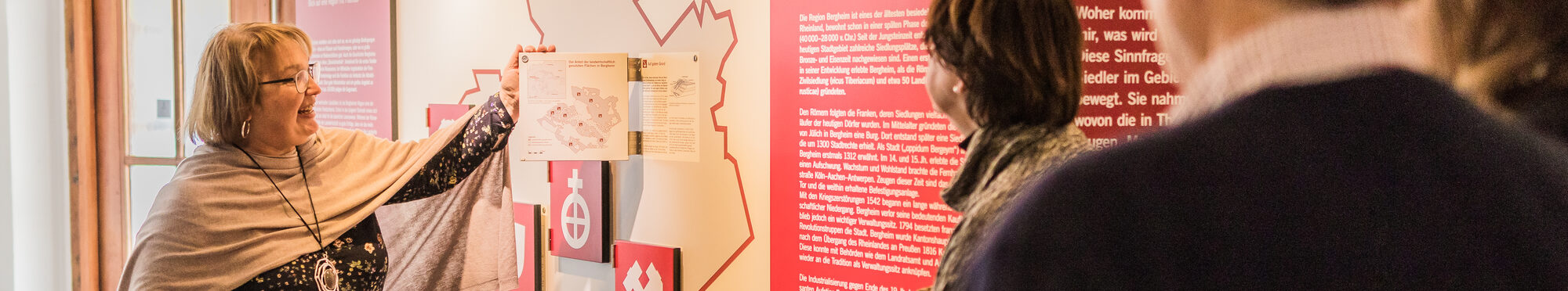 Eine Frau zeigt mit dem Finger auf eine Karte während einer Führung durch ein Museum